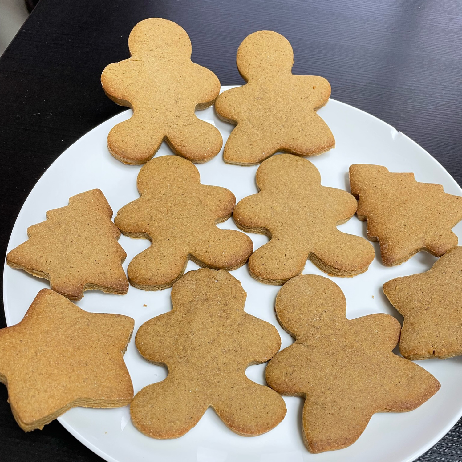 Gingerbread cookies in gingerbread man, tree, and star shapes sitting on a plate